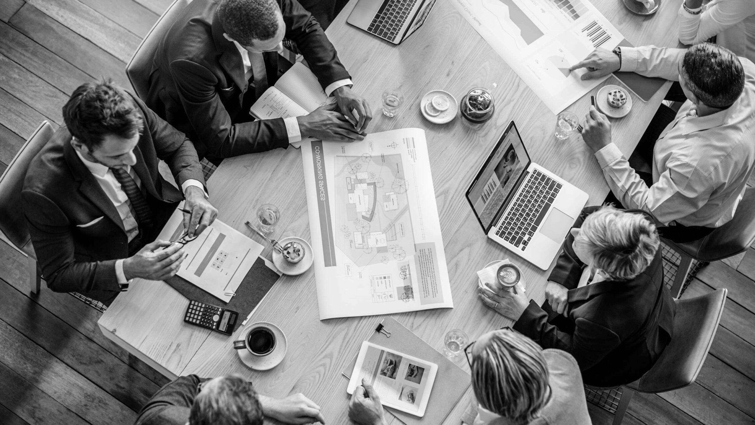 Nine senior executives seated around a walnut boardroom table in a high-floor European corporate tower engaged in boardroom dynamics discussion