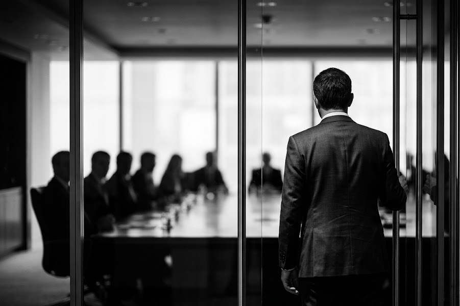 New executive pausing in the doorway of a boardroom before entering — the first 100 days as an outsider